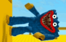 a blue stuffed animal with a big mouth is laying on its back on a yellow surface .