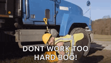 a man is laying on the ground next to a blue truck with the words `` dont work too hard boo '' .