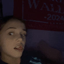 a girl is sticking her tongue out in front of a wall 2024 sign .