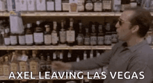 a man is standing in front of a shelf of liquor bottles and says `` axel leaving las vegas '' .
