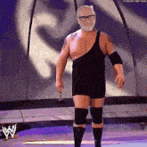 a man in a wrestling outfit is standing on a stage in front of a w logo .