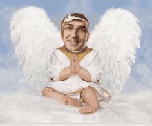 a man dressed as an angel is sitting on a white blanket