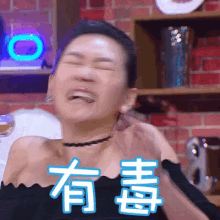 a woman is making a funny face in front of a brick wall with chinese writing on it