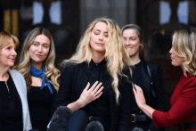 a group of women are standing around a blonde woman with her eyes closed