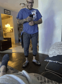 a man wearing a blue shirt that says ' pepsi ' on it is standing in a living room