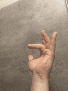 a person 's hand is making an ok sign on a gray background