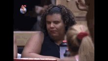 a woman with curly hair is sitting at a table with a tray of food in front of her .