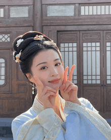 a woman in a blue dress making a peace sign with her hands