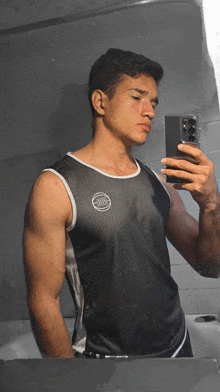 a man taking a picture of himself in a mirror wearing a black tank top