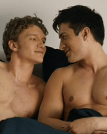 two shirtless men are looking at each other on a bed