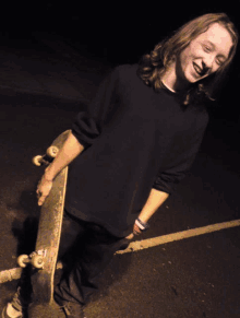 a young man is holding a skateboard and smiling