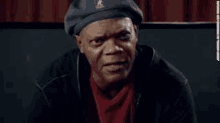 a man wearing a beret and a red shirt is making a face .