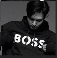 a black and white photo of a man wearing a black boss hoodie