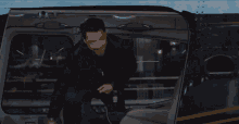 a man in a black leather jacket is getting out of a car