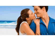 a man and woman are kissing on the beach .