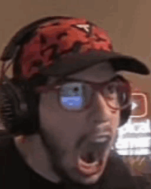 a man wearing headphones , glasses and a hat is making a funny face .