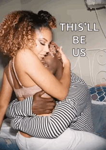a man and a woman are hugging each other on a bed and the woman is kissing the man 's forehead .