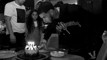 a man blowing out candles on a cake while wearing a black shirt that says ' nightmare ' on it