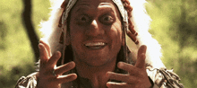 a man wearing a native american headdress is smiling with his hands outstretched