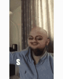 a bald man with a beard is wearing a blue shirt and making a face .