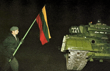 a man holds a flag in front of a tank with the number 221