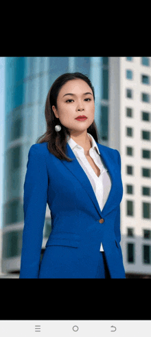 a woman in a blue suit and white shirt stands in front of a building