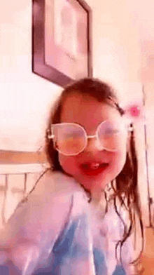 a little girl wearing sunglasses is making a funny face in a room .