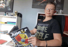 a young boy is sitting at a desk reading a magazine called junior