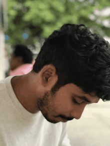 a man with a beard and a white shirt looks down