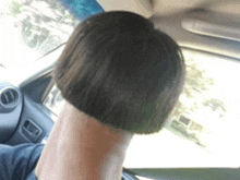 a woman with a very short haircut is sitting in a car