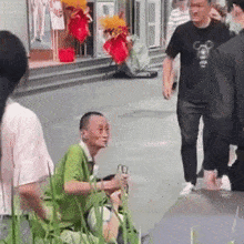 a man in a green shirt is sitting on the sidewalk next to a woman in a black shirt .