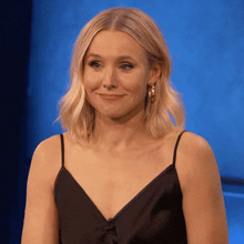 a woman wearing a black dress and hoop earrings smiles