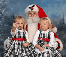 two little girls are posing for a photo with santa claus