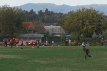 a group of people on a field with one wearing a blue shirt that says ' soccer ' on it