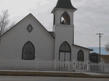 a white church with a black steeple and stained glass