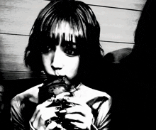 a black and white photo of a girl eating a hamburger