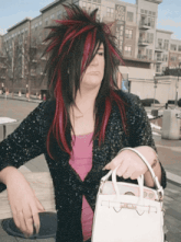 a woman with red and black hair is holding a white purse