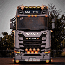 a gray scania super truck is parked in front of a fence