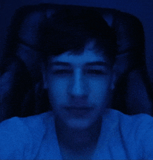 a man in a white shirt is taking a selfie with a blue light behind him