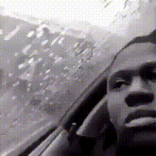 a black and white photo of a man sitting in a car