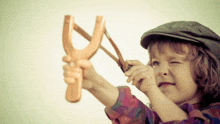 a young boy is holding a wooden slingshot in his hand