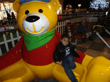 a boy sitting on a yellow teddy bear wearing a black jacket with the number 33 on it