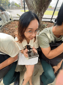 a girl wearing glasses is holding a cell phone in her hand