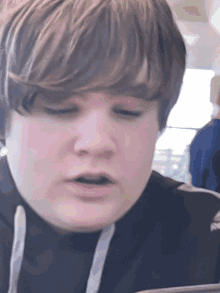 a close up of a young boy 's face with a hoodie on