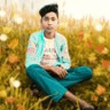 a young boy is sitting in the grass with his legs crossed .