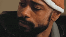 a man with a beard is wearing a white headband and earrings