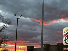 a burger king sign in front of a cloudy sunset