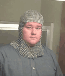 a man is wearing a chain mail helmet and taking a selfie .