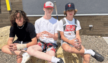 three boys are sitting on a rock and one has a shirt that says heat on it