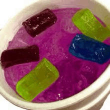 a bucket filled with ice cubes of different colors in a purple liquid .